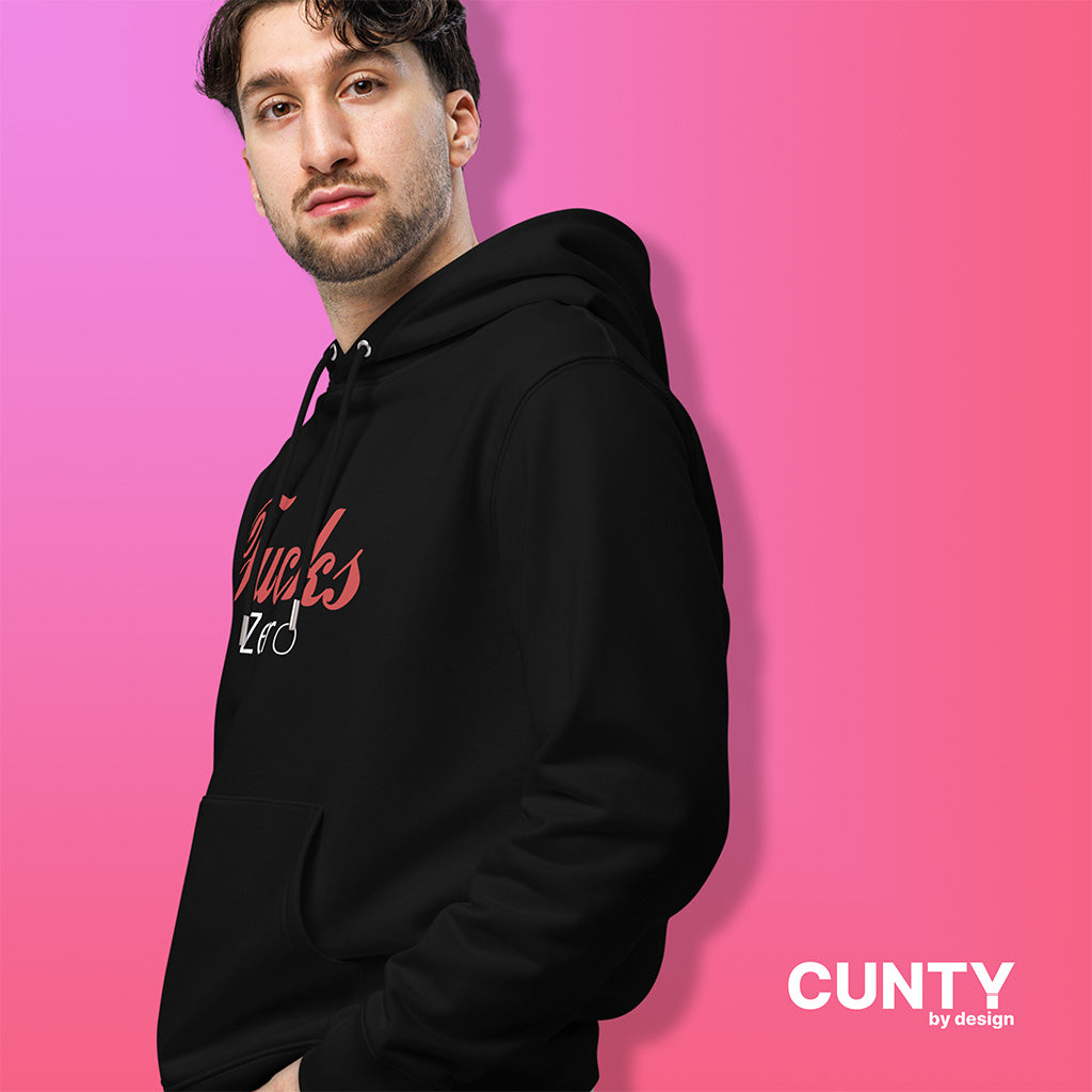 Stylish man wearing a black Fucks Zero hoodie by Cunty by Design, standing against a bold pink gradient background.