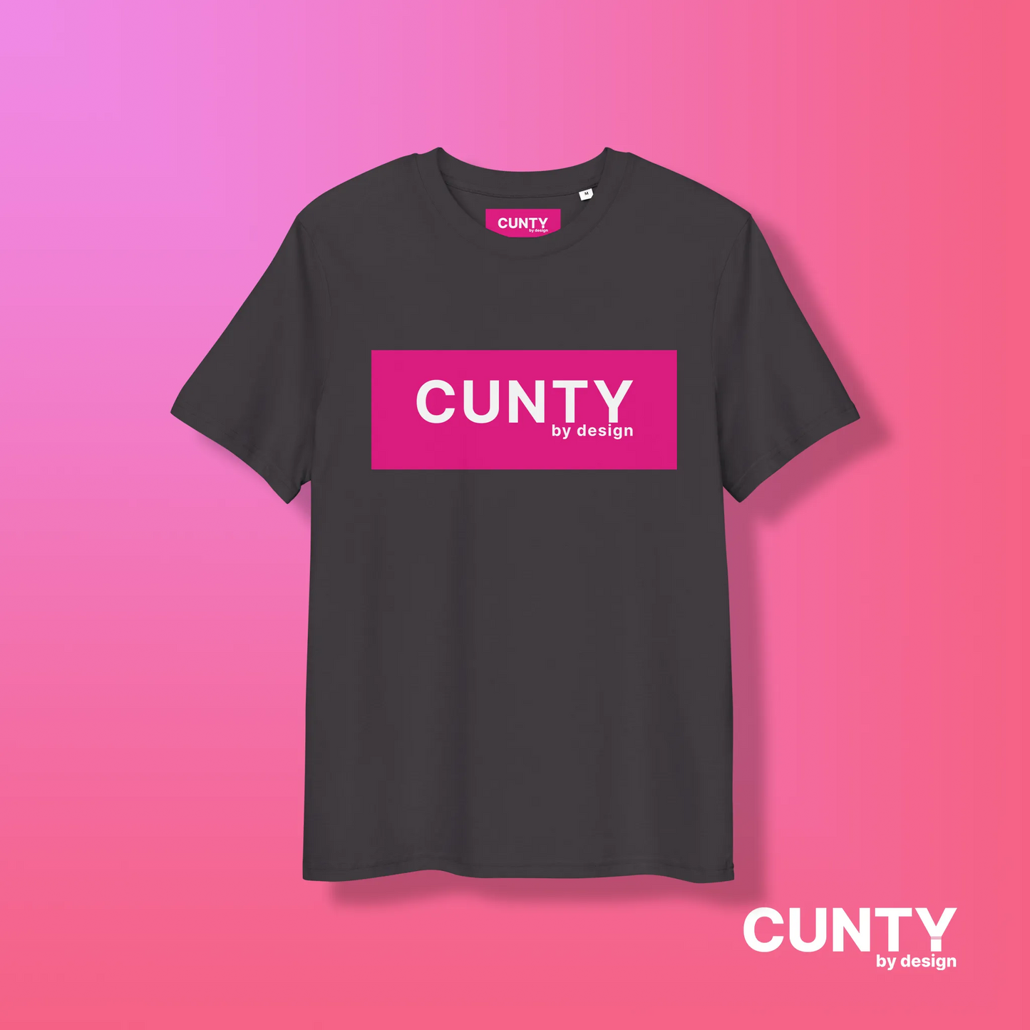 Anthracite with Fuchsia Design: A dark grey unisex t-shirt featuring the bold "Cunty by Design" logo in a vibrant fuchsia rectangle, displayed on a pink gradient background.