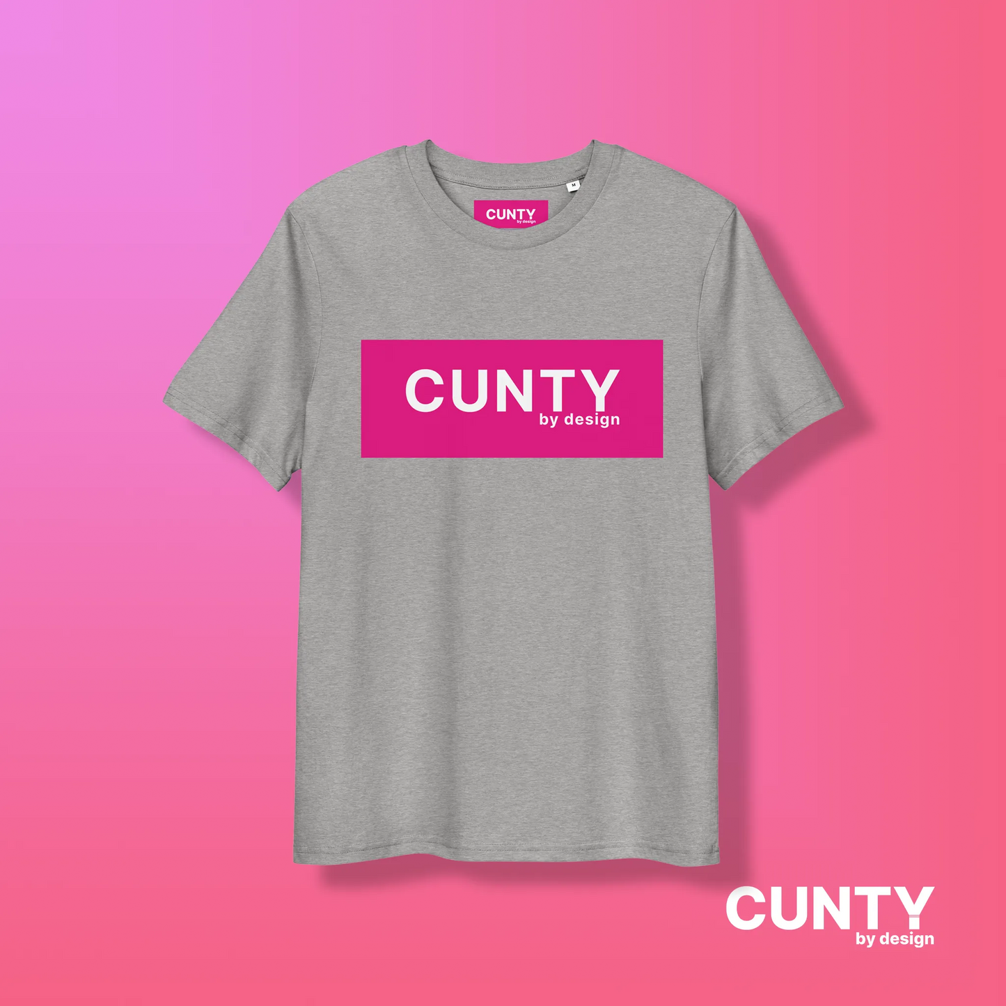 Heather Grey with Fuchsia Design: A light heather grey unisex t-shirt featuring the "Cunty by Design" logo in a fuchsia rectangle, styled on a pink gradient background.