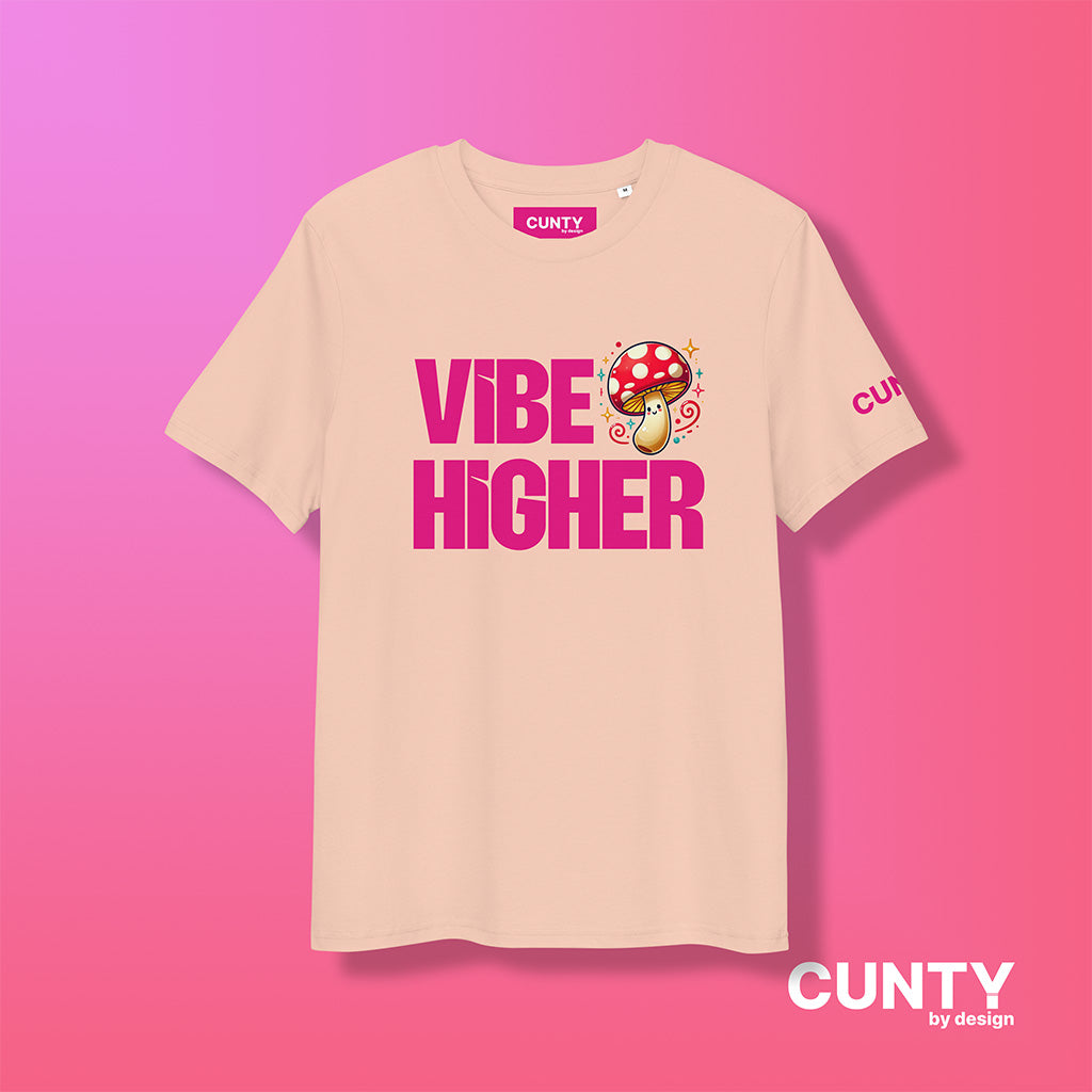 fraiche-peche organic cotton t-shirt featuring the bold text "Vibe Higher" in vibrant pink, paired with a colorful magic mushroom graphic. The shirt has a unisex design with a Cunty by Design logo on the sleeve, and inside neck label displayed against a fuchsia background.